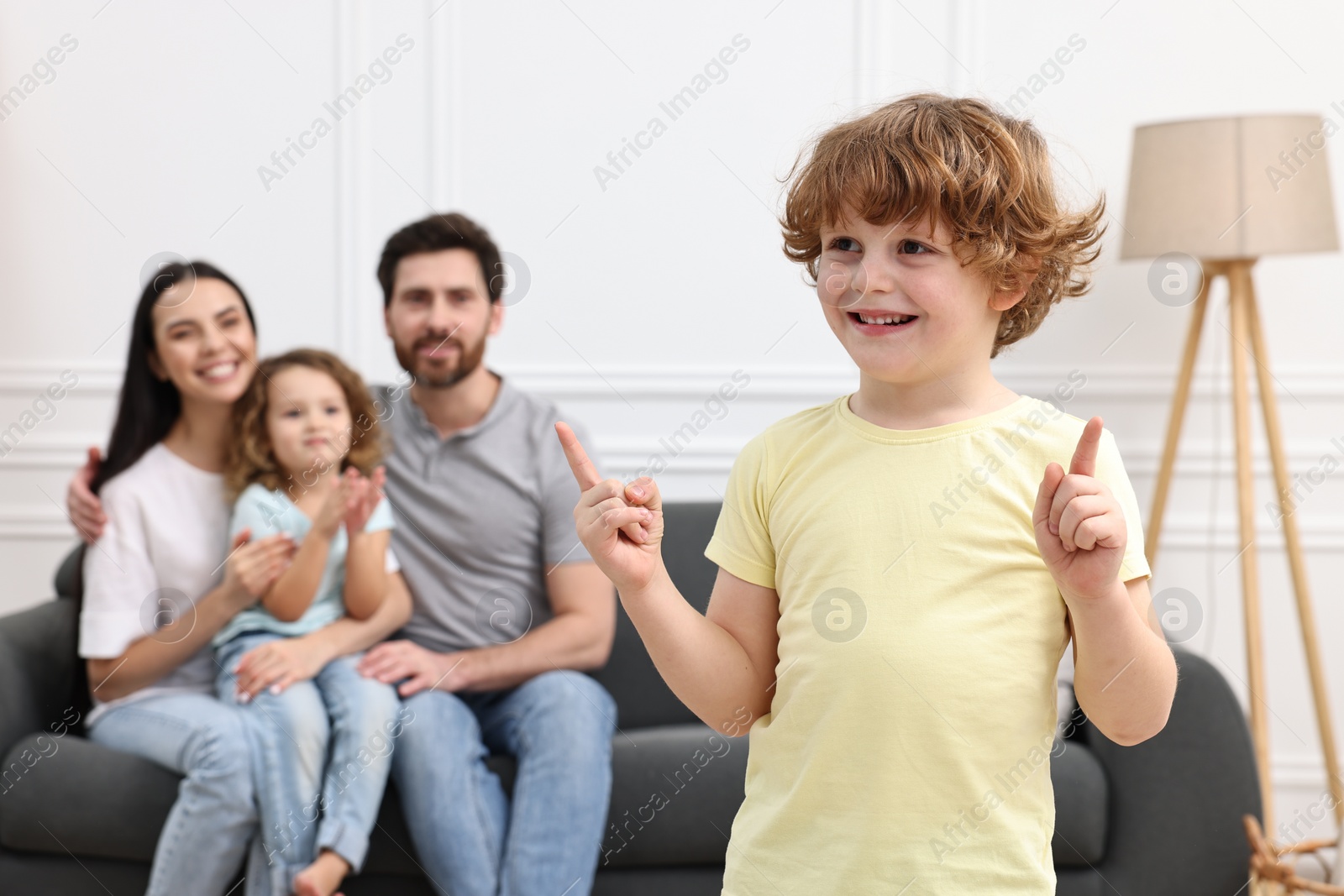 Photo of Happy family having fun at home. Son dancing while his relatives resting on sofa