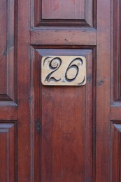 Plate with house number twenty six on wooden door, closeup