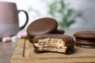 Photo of Tasty choco pies on wooden board, closeup view