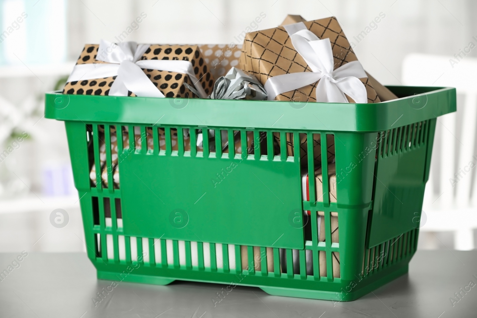 Photo of Shopping basket with different gift boxes on light table indoors