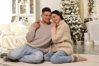 Photo of Happy couple on floor in room with Christmas tree