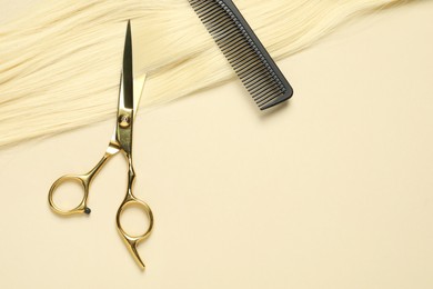 Photo of Professional scissors and comb with blonde hair strand on beige background, top view. Space for text