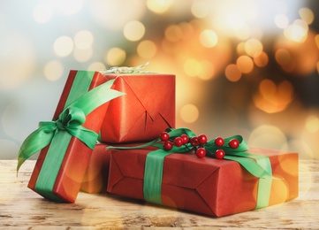 Image of Christmas gift boxes on wooden table against blurred background, bokeh effect