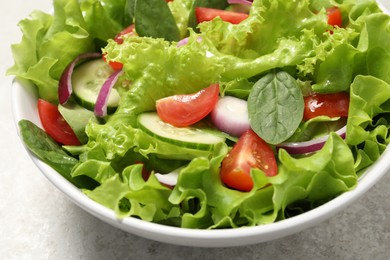 Delicious salad in bowl on light grey table, closeup