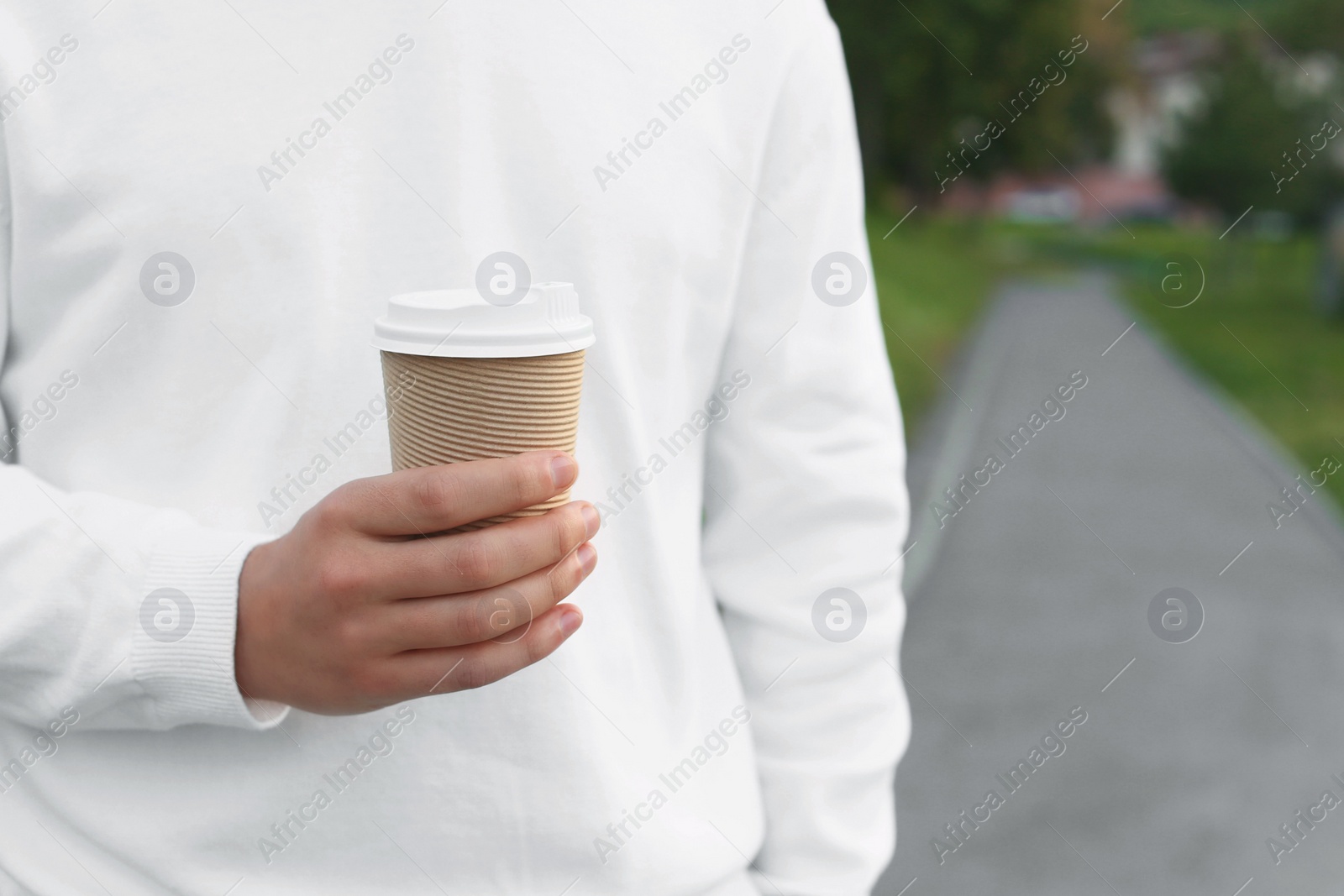 Photo of Coffee to go. Man with paper cup of drink outdoors, closeup