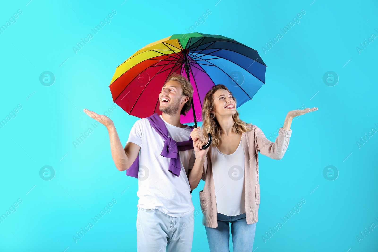 Photo of Couple with rainbow umbrella on color background