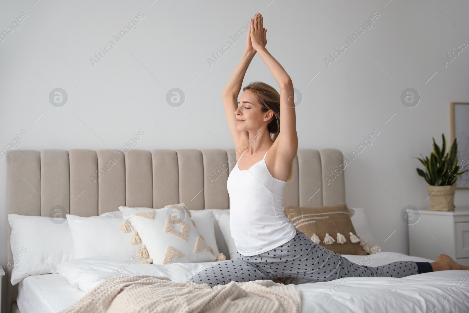 Photo of Young woman doing gymnastics on bed at home. Morning fitness