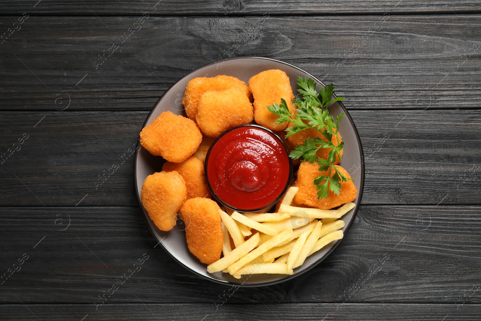 Photo of Tasty fried chicken nuggets with garnish on wooden table, top view