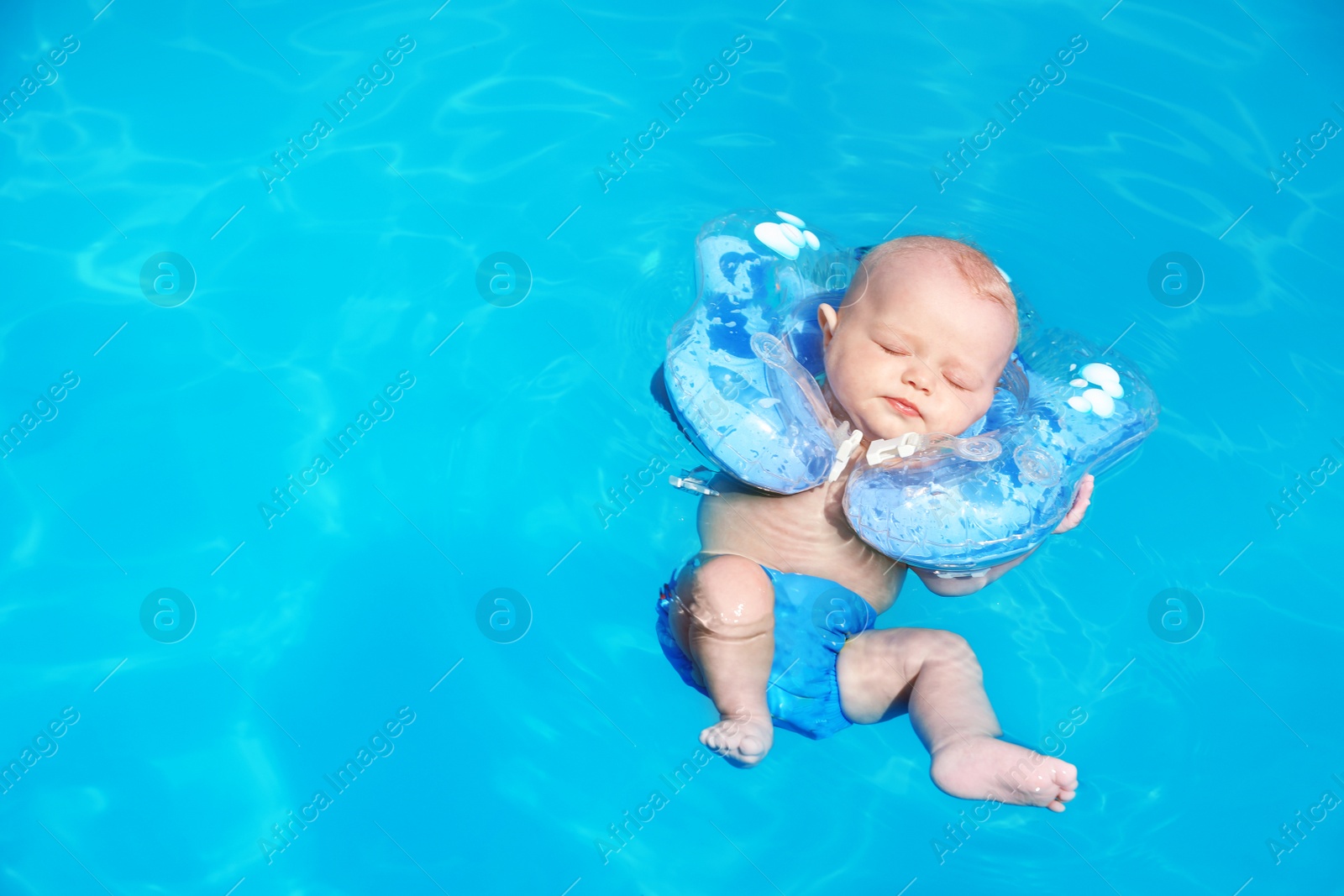 Photo of Cute little baby with inflatable neck ring in swimming pool on sunny day, outdoors