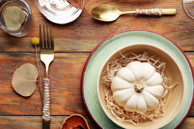 Autumn table setting with pumpkin and decor on wooden background, flat lay