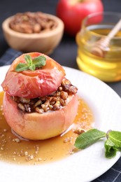 Tasty baked apple with nuts, honey and mint on table, closeup