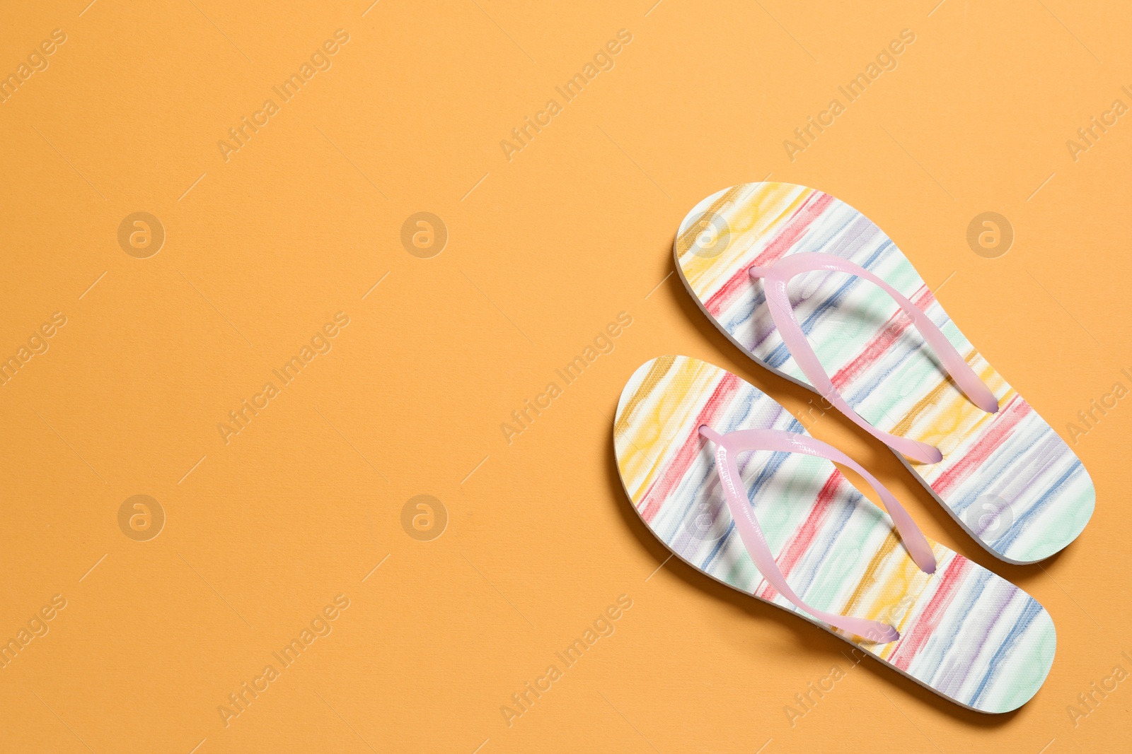 Photo of Bright flip flops on color background, top view with space for text. Beach accessories