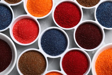 Bowls of different food coloring on light grey table, flat lay