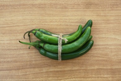 Photo of Green ripe chili peppers on wooden table, top view