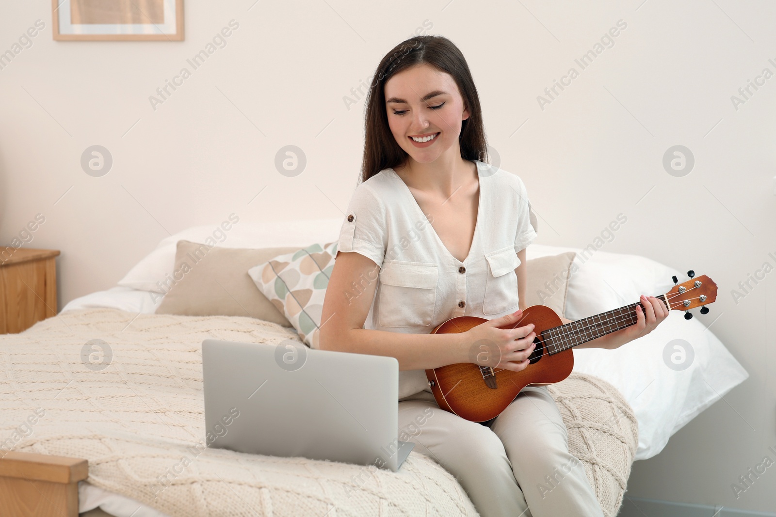 Photo of Woman learning to play ukulele with online music course at home. Space for text