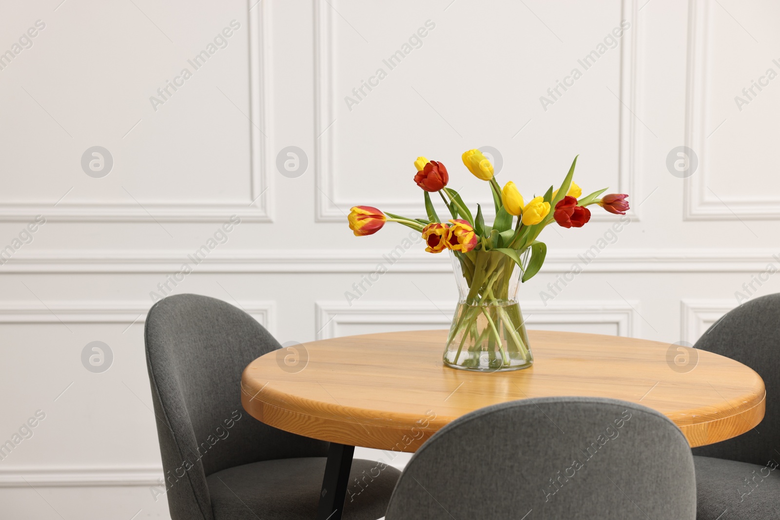 Photo of Vase with beautiful tulips on table in dining room