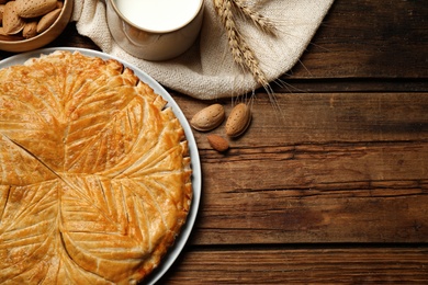 Photo of Traditional galette des rois and ingredients on wooden table, flat lay. Space for text