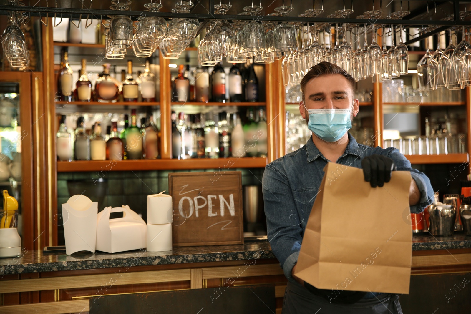 Photo of Waiter with packed takeout order in restaurant. Food service during coronavirus quarantine