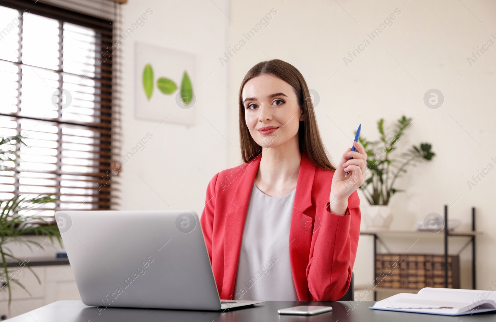 Photo of Young businesswoman using laptop at table in office