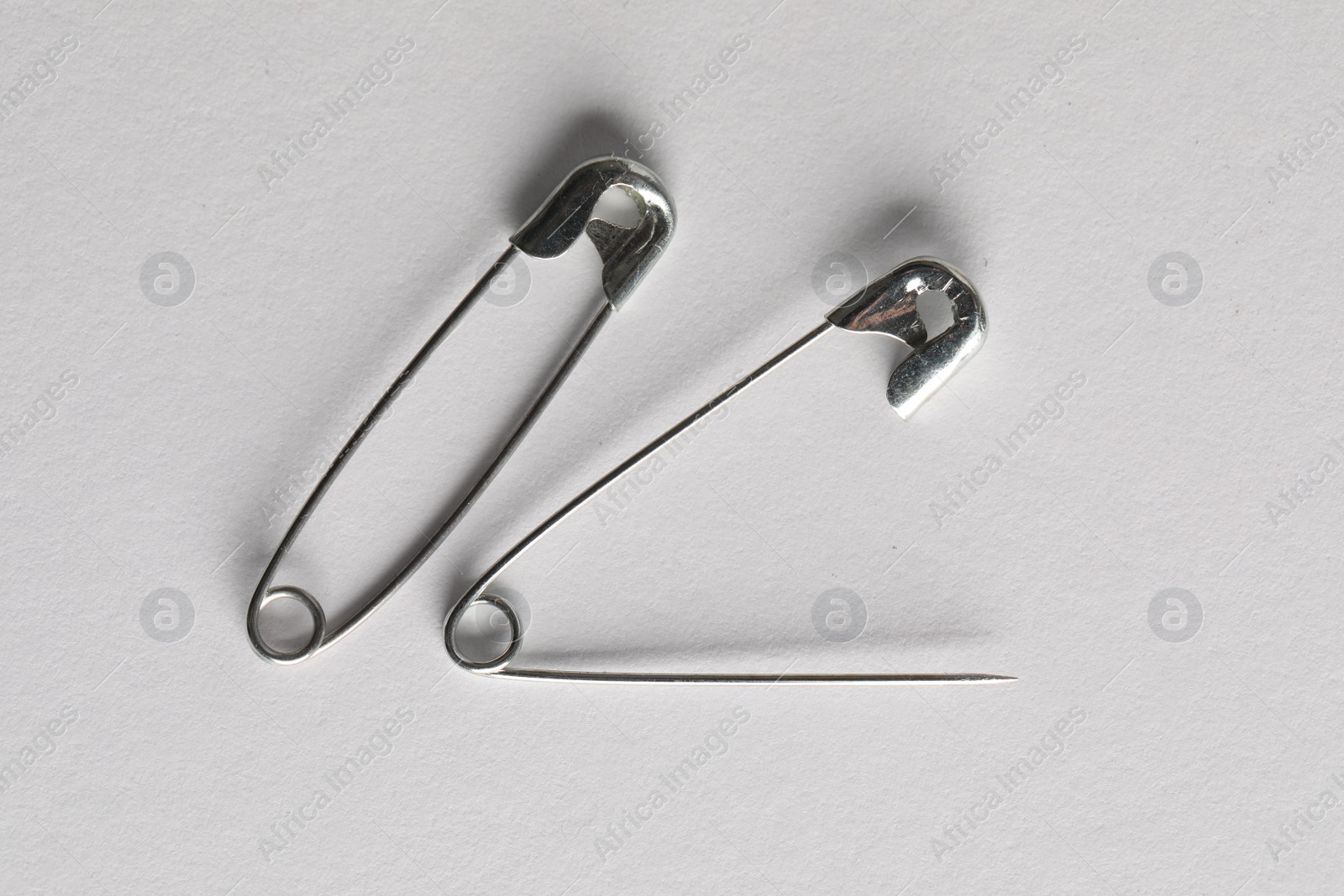 Photo of Metal safety pins on white background, flat lay