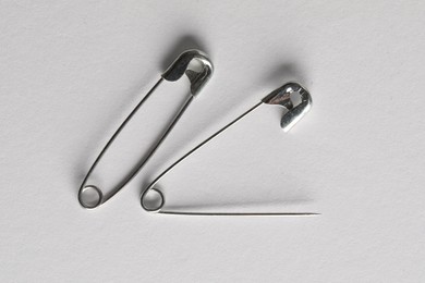 Metal safety pins on white background, flat lay