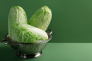 Fresh Chinese cabbages in colander on green background, closeup. Space for text