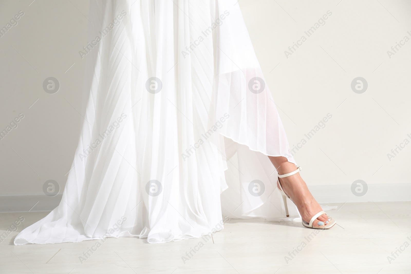 Photo of Young bride wearing beautiful wedding dress near light wall, closeup