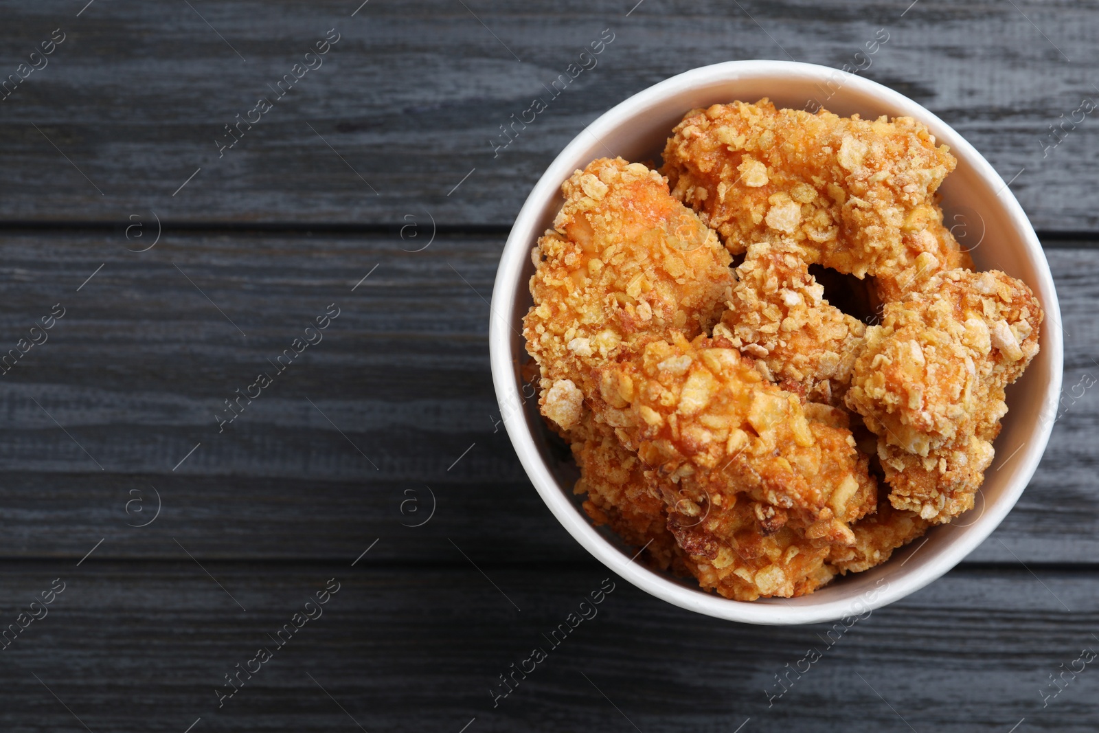 Photo of Bucket with yummy nuggets on dark wooden table, top view. Space for text