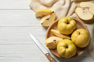 Photo of Fresh ripe organic quinces and knife on white wooden table, flat lay. Space for text