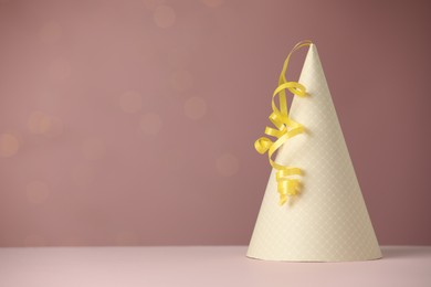 Photo of Party hat and serpentine streamers on dusty pink background, space for text