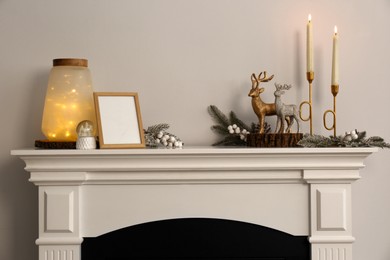 Stylish interior decorations on fireplace near white wall indoors