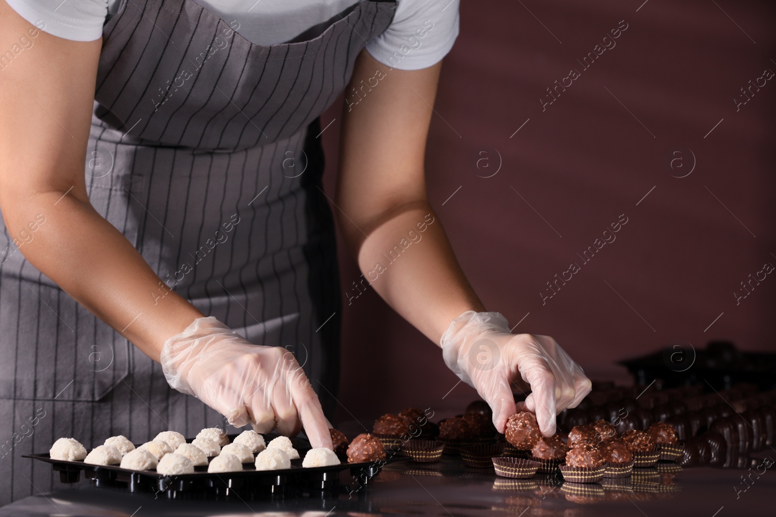 Photo of Woman packing delicious candies at production line, closeup