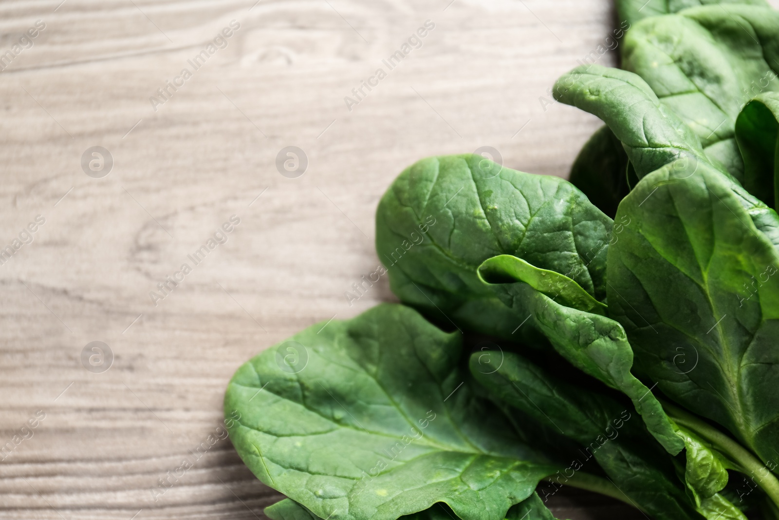 Photo of Fresh green healthy spinach leaves on wooden table, closeup