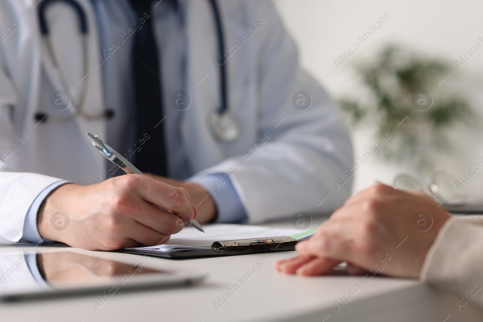 Photo of Professional doctor working with patient at white table in hospital, closeup