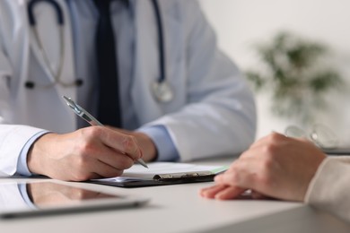 Photo of Professional doctor working with patient at white table in hospital, closeup