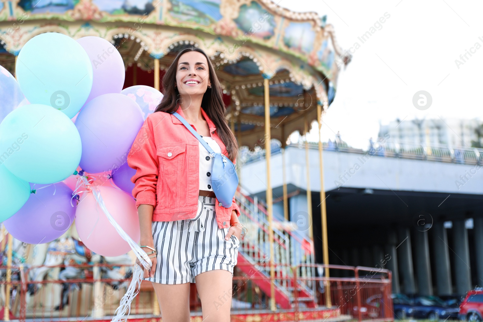 Photo of Attractive young woman with color balloons near carousel