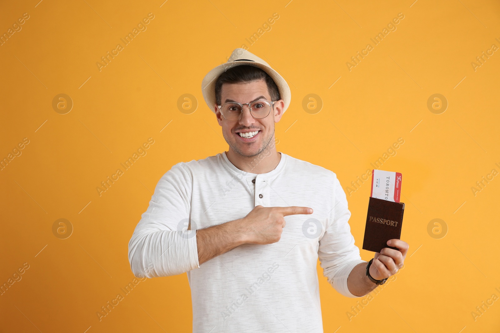 Photo of Male tourist holding passport with ticket on yellow background