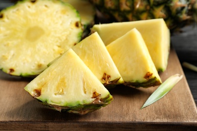 Photo of Fresh sliced pineapple on wooden board, closeup