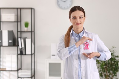 Photo of Mammologist with pink ribbon in hospital, space for text. Breast cancer awareness