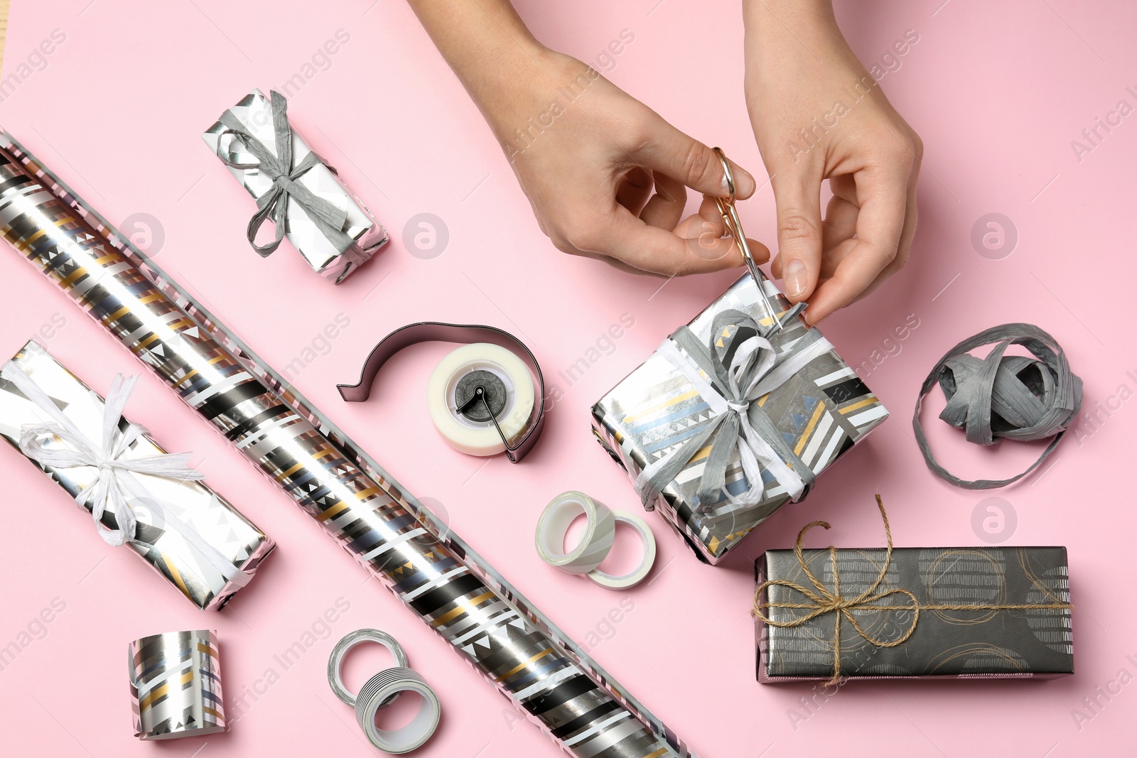 Photo of Woman decorating gift box on color background, top view