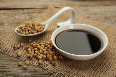 Soy sauce in bowl and beans on wooden table, closeup