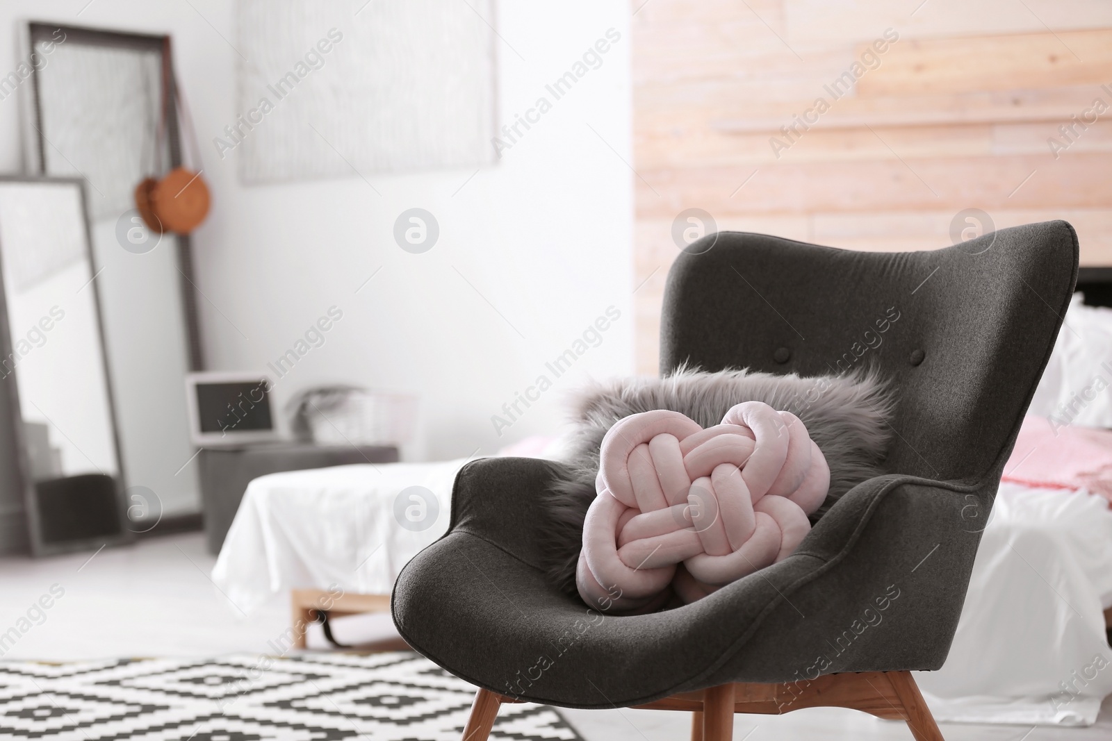 Photo of Pillows on dark armchair in room interior. Unusual cushion design