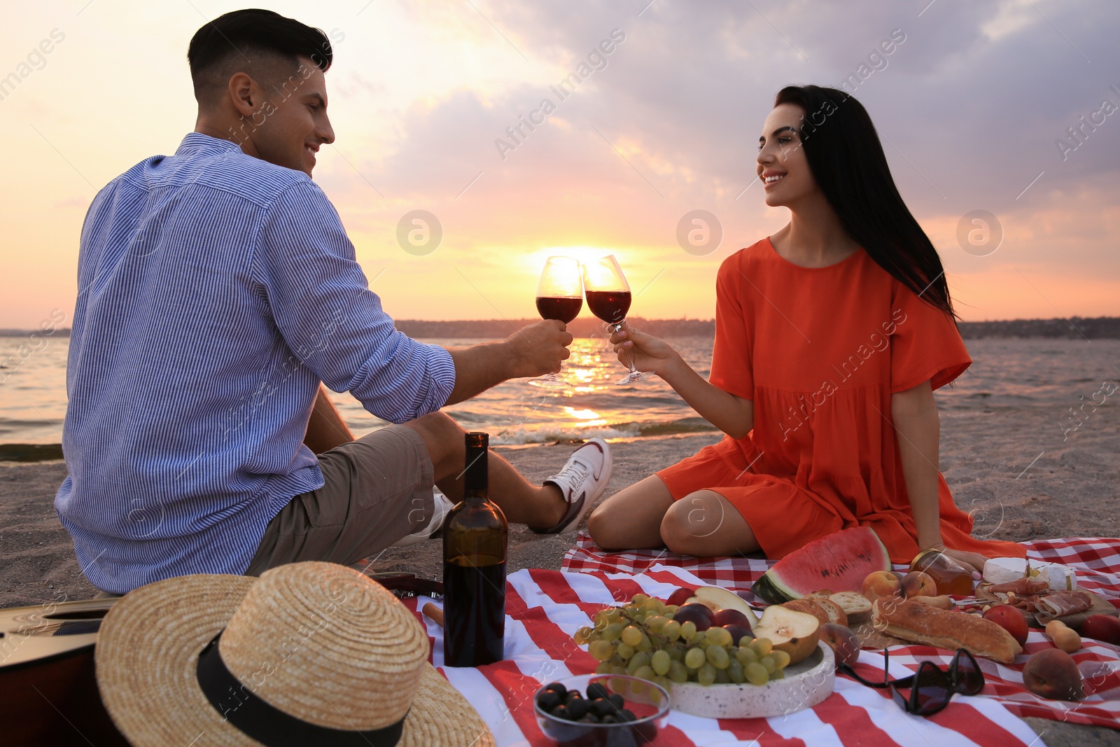 Photo of Lovely couple having picnic near river at sunset