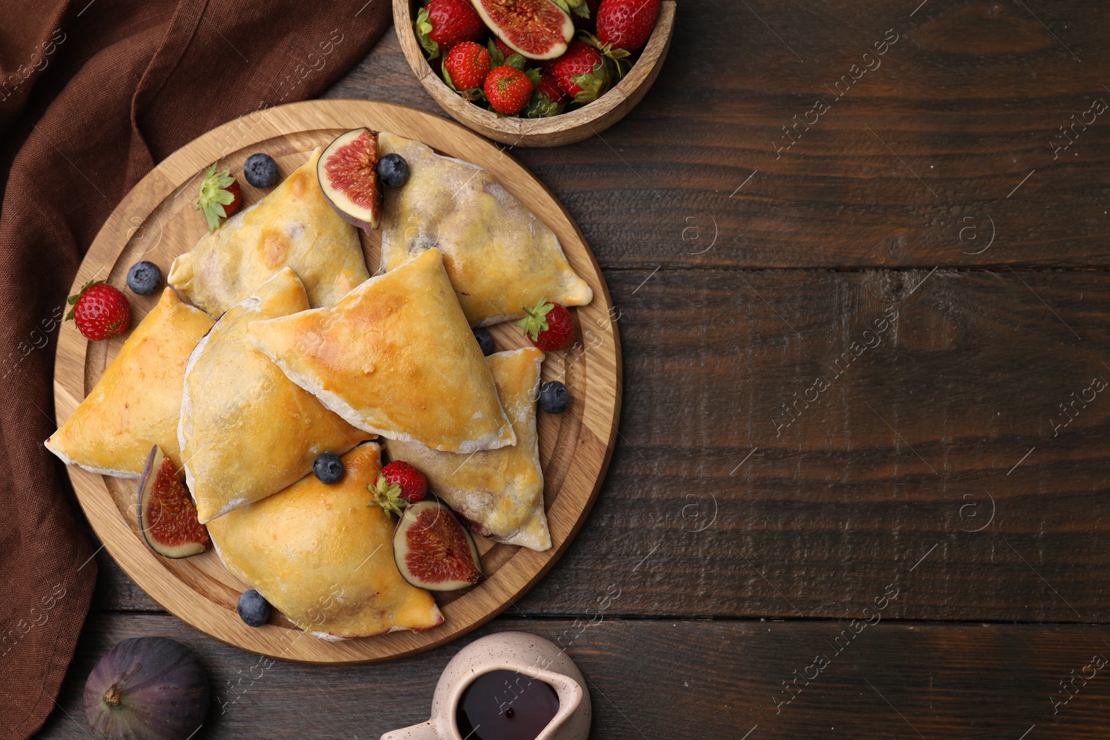 Photo of Delicious samosas with figs and berries on wooden table, flat lay. Space for text