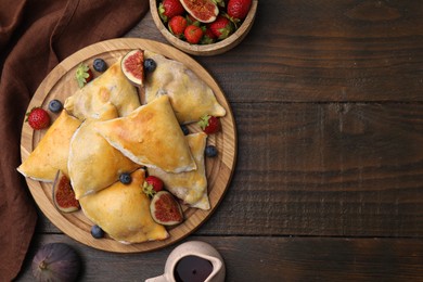 Delicious samosas with figs and berries on wooden table, flat lay. Space for text