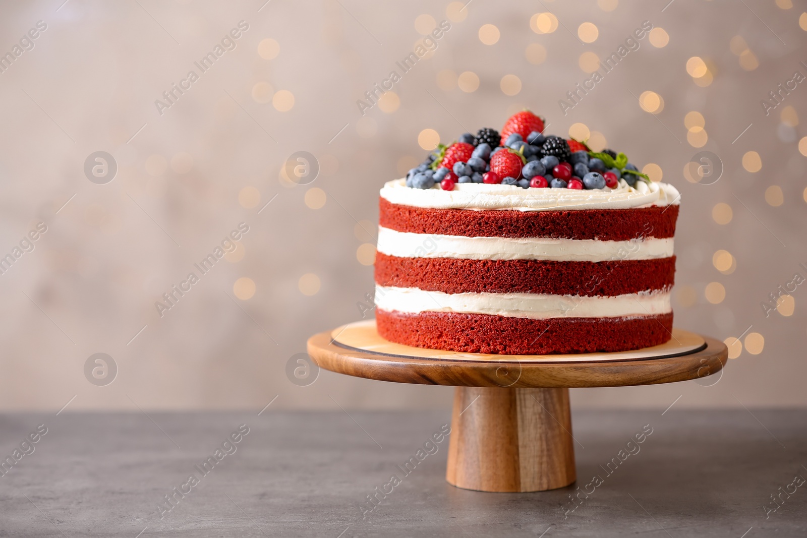 Photo of Stand with delicious homemade red velvet cake and space for text against blurred lights