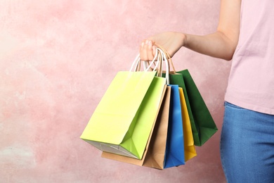 Photo of Woman holding paper shopping bags on color background