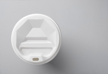 One paper cup with white lid on light grey background, top view with space for text. Coffee to go