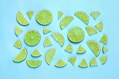 Photo of Juicy fresh lime slices on light blue background, flat lay