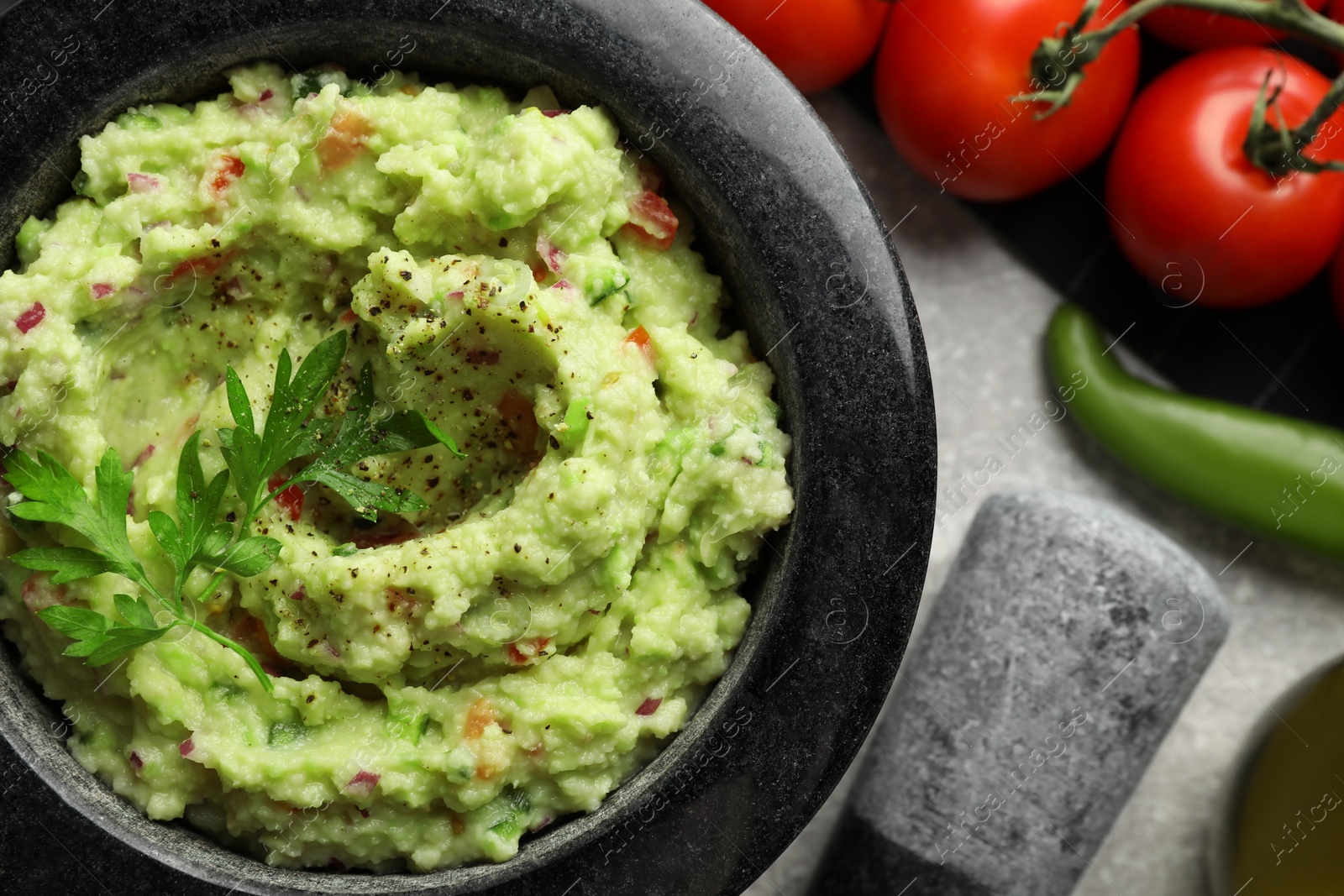 Photo of Delicious guacamole and ingredients on grey table, flat lay